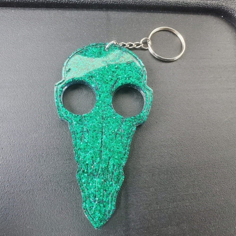 Self defense bird skull key chain with blue and green glitter. Made from resin.